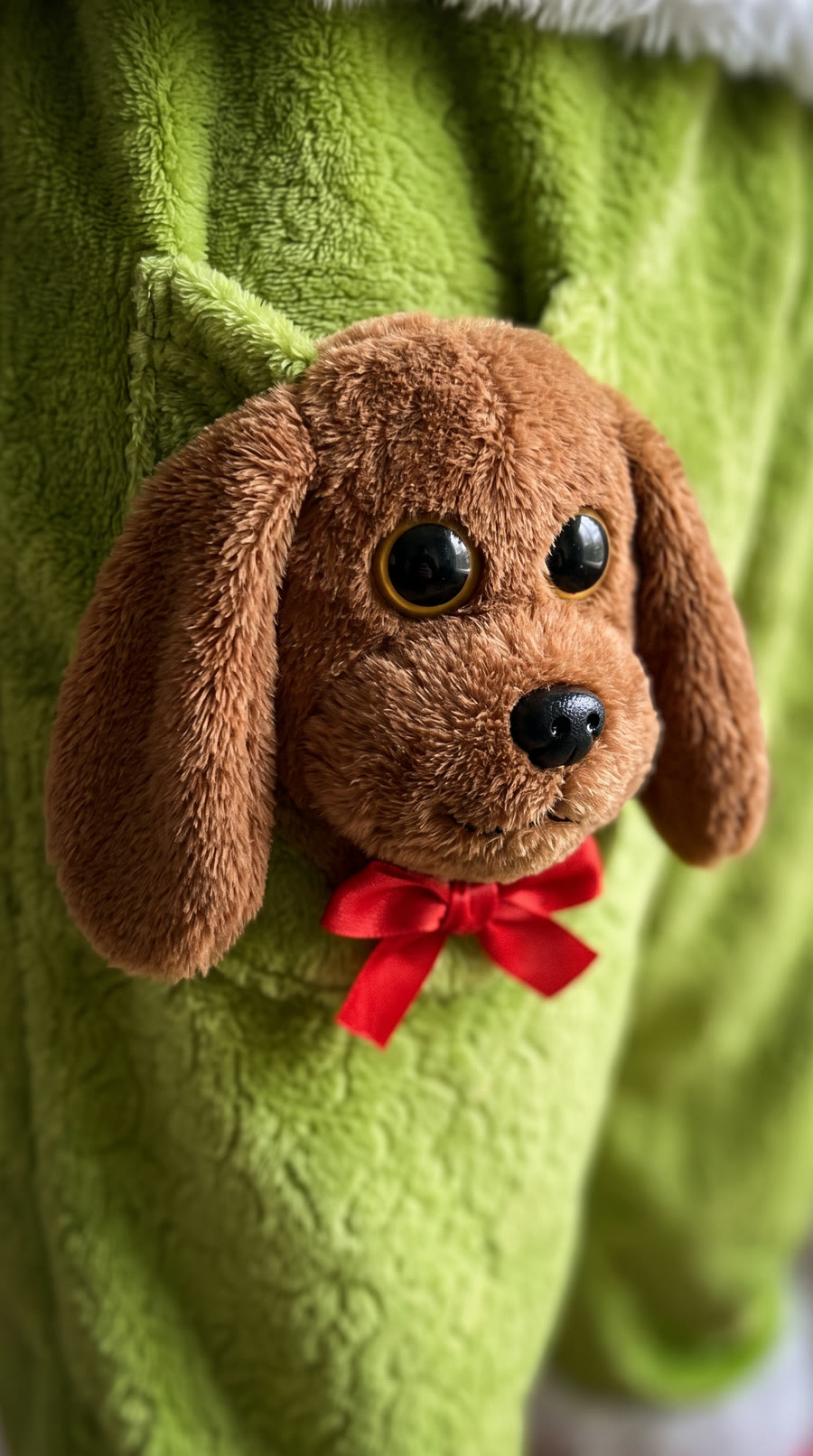 Close up of the brown plush dog pocket with red bow